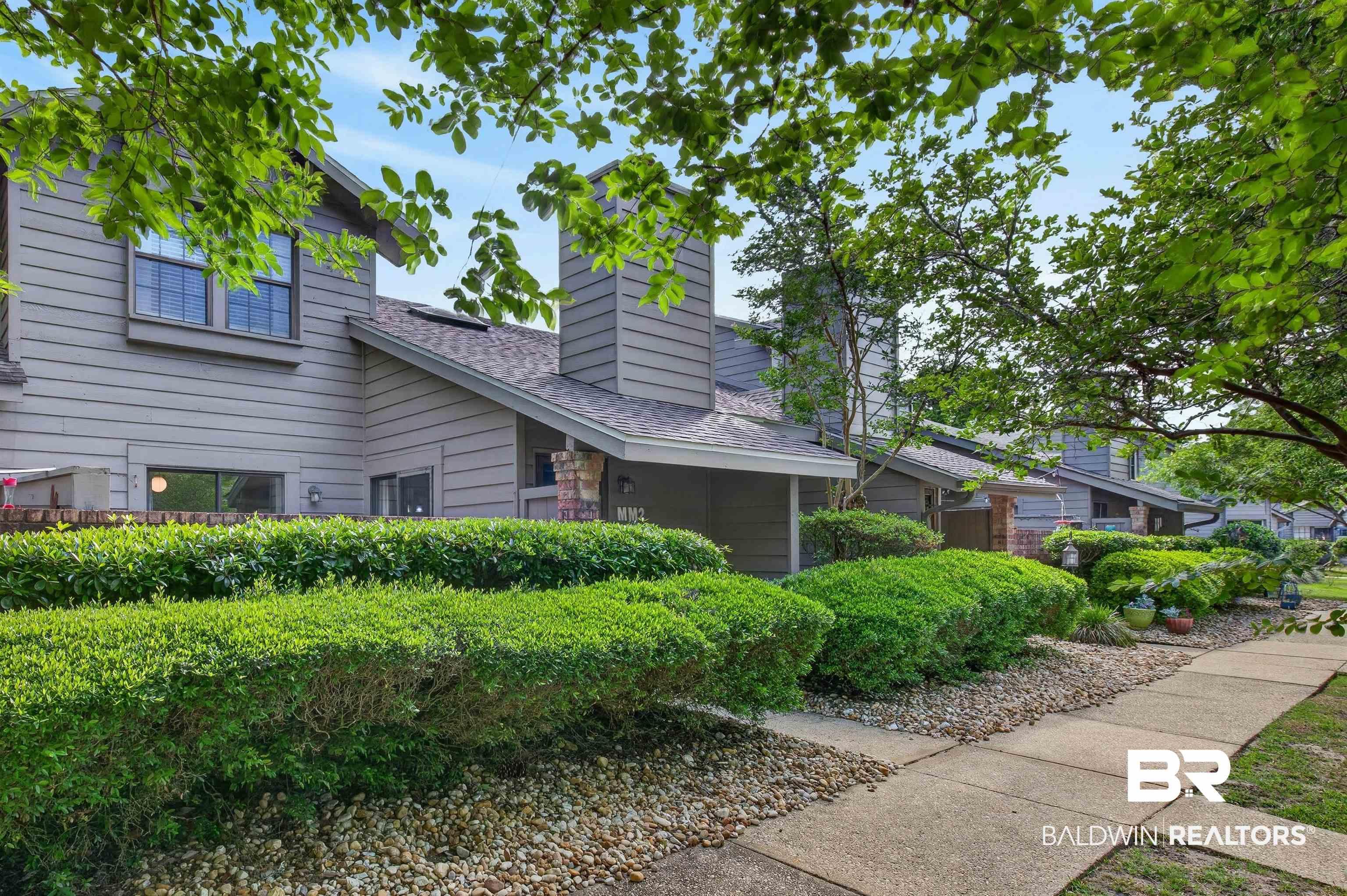 Image 3: Contemporary townhome exterior featuring gray siding, a pitched roof, and a prominent chimney