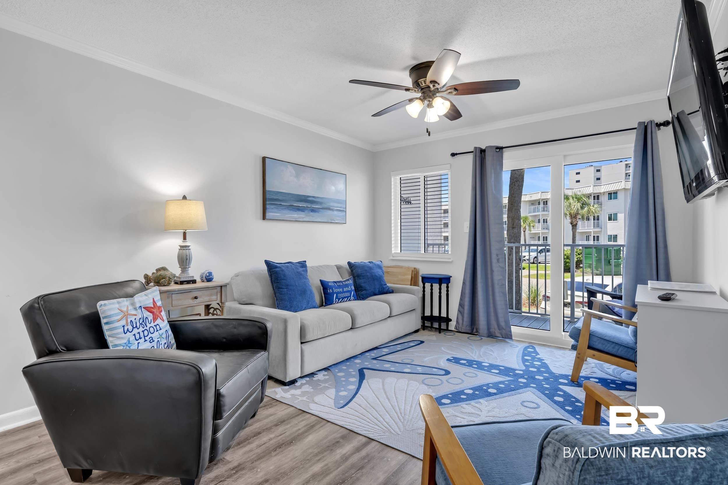 Image 2: Living space featuring wood-finish flooring, a ceiling fan, crown molding, and a sliding glass door to an outdoor balcony