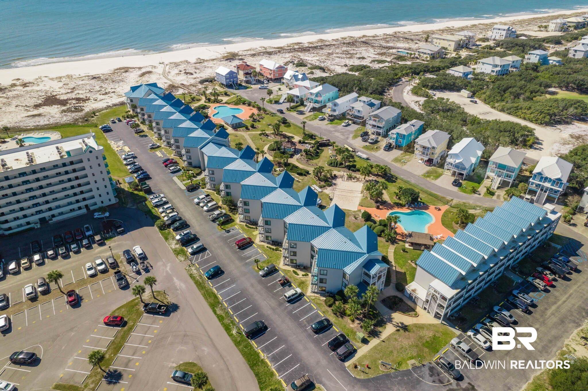 Image 1: Bird's eye view of expansive beach and a pool area