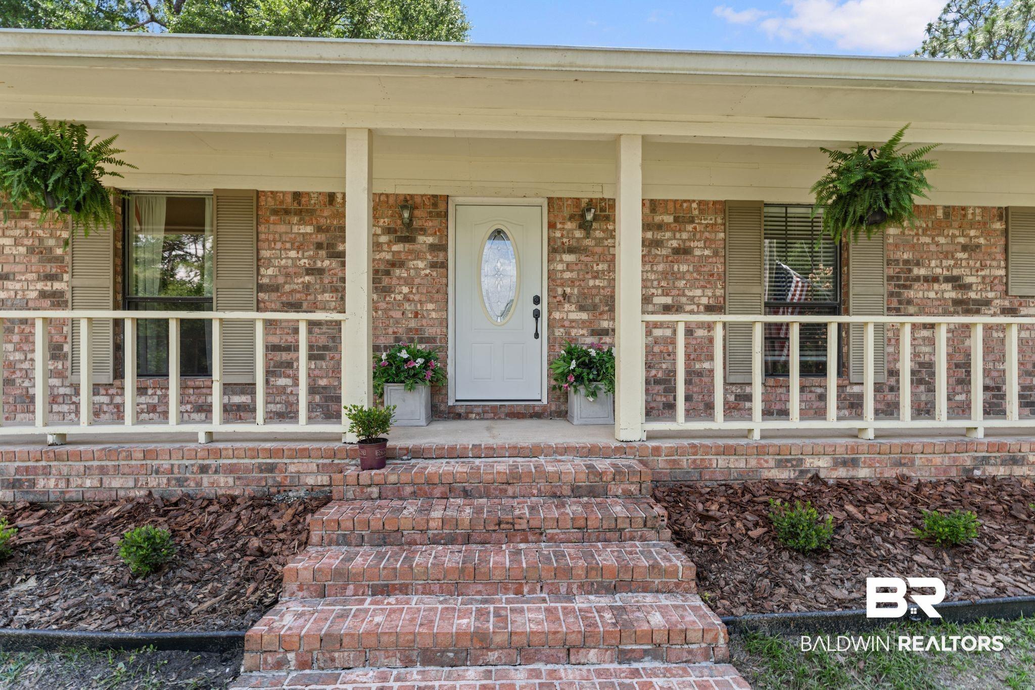 Image 2: Brick exterior with a covered front porch, featuring multiple brick steps, white railing, and decorative window shutters