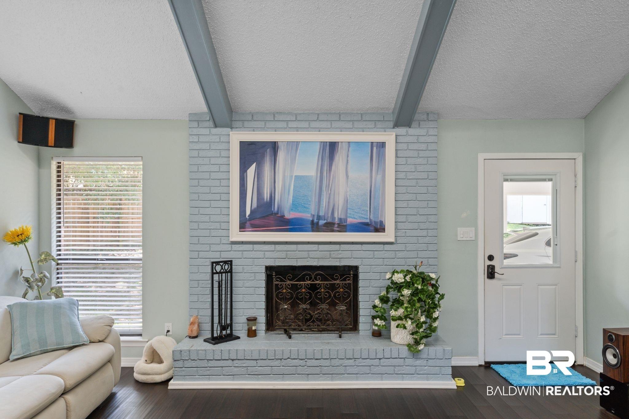 Image 3: Living area featuring a painted brick fireplace with a decorative screen and an exposed beam ceiling