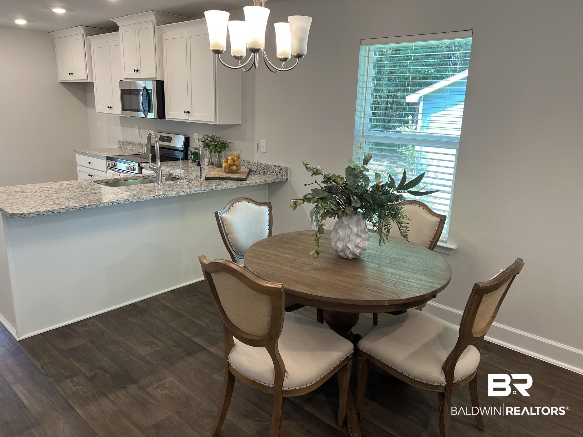 Image 2: Kitchen and dining area featuring white cabinetry, stainless steel appliances, and a granite-finish countertop with an undermount sink