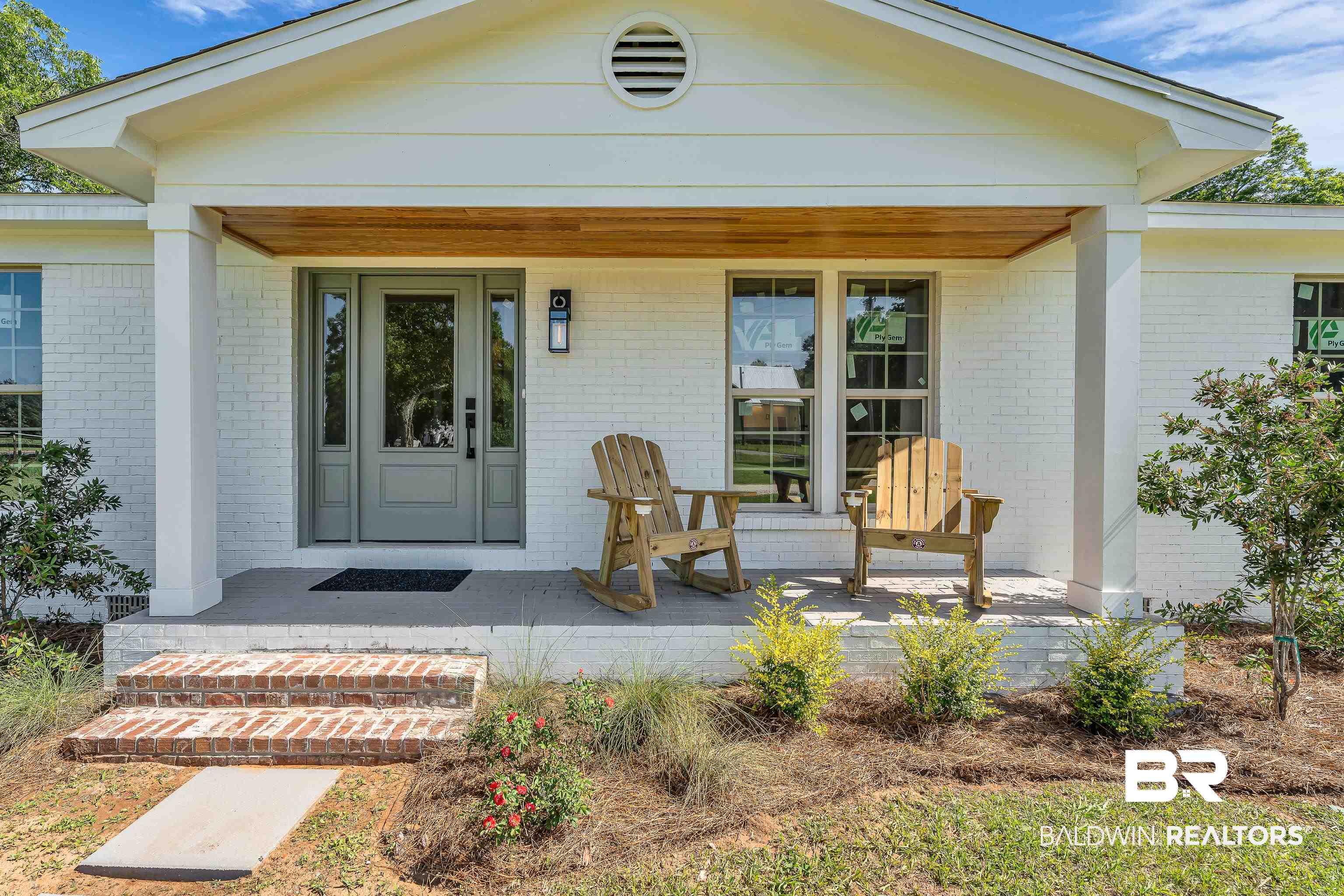 Image 2: White brick exterior with a covered porch featuring a wood-finish ceiling, gray paneled entry door with sidelights, and brick porch steps