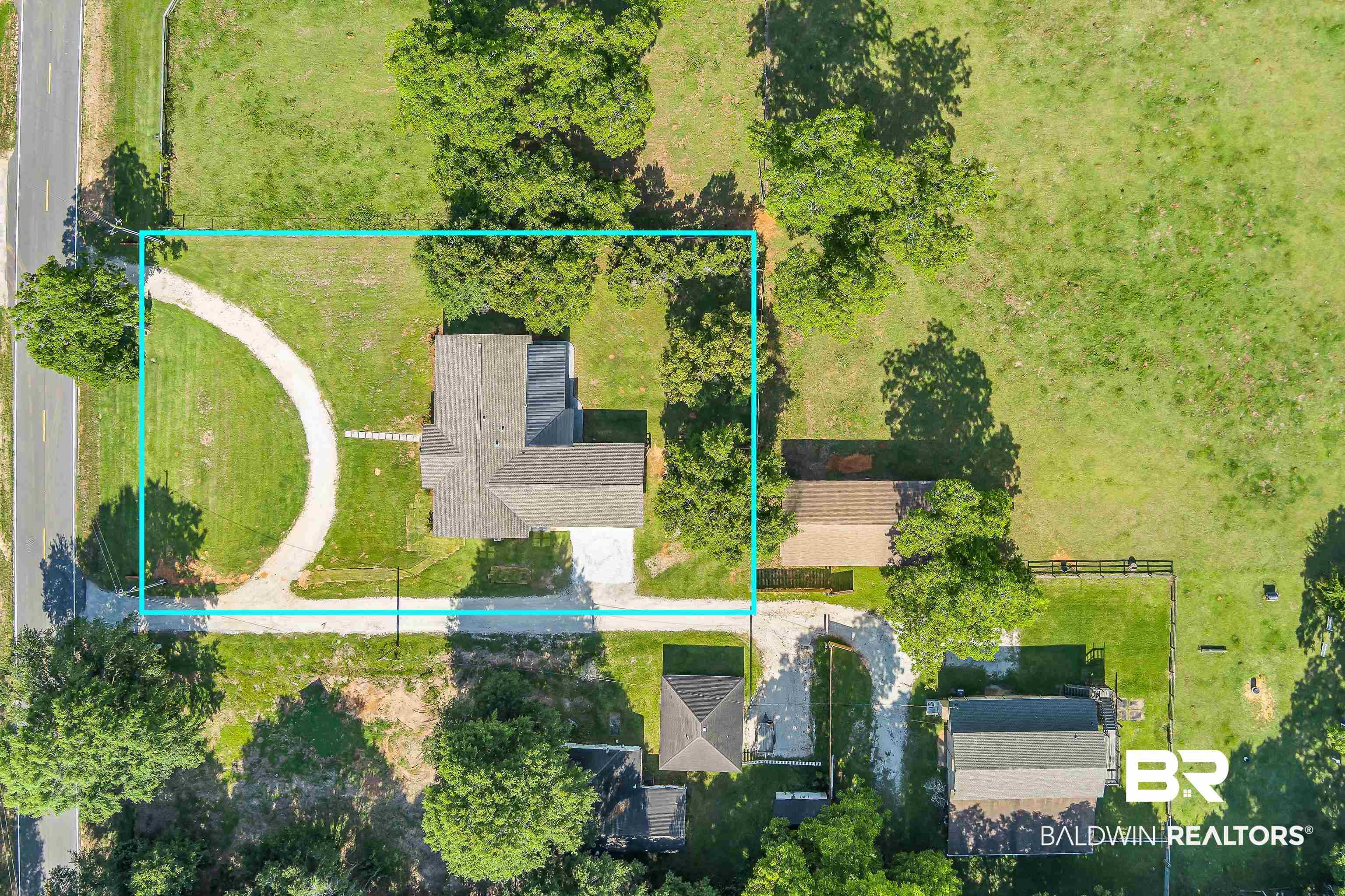Image 3: Aerial perspective showcasing a property with a gabled roofline, a curved gravel driveway, and surrounding green spaces