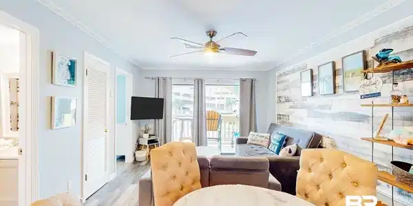 Image 4: Open-concept living area featuring wood-finish flooring, a decorative shiplap accent wall, and a ceiling fan with integrated lighting