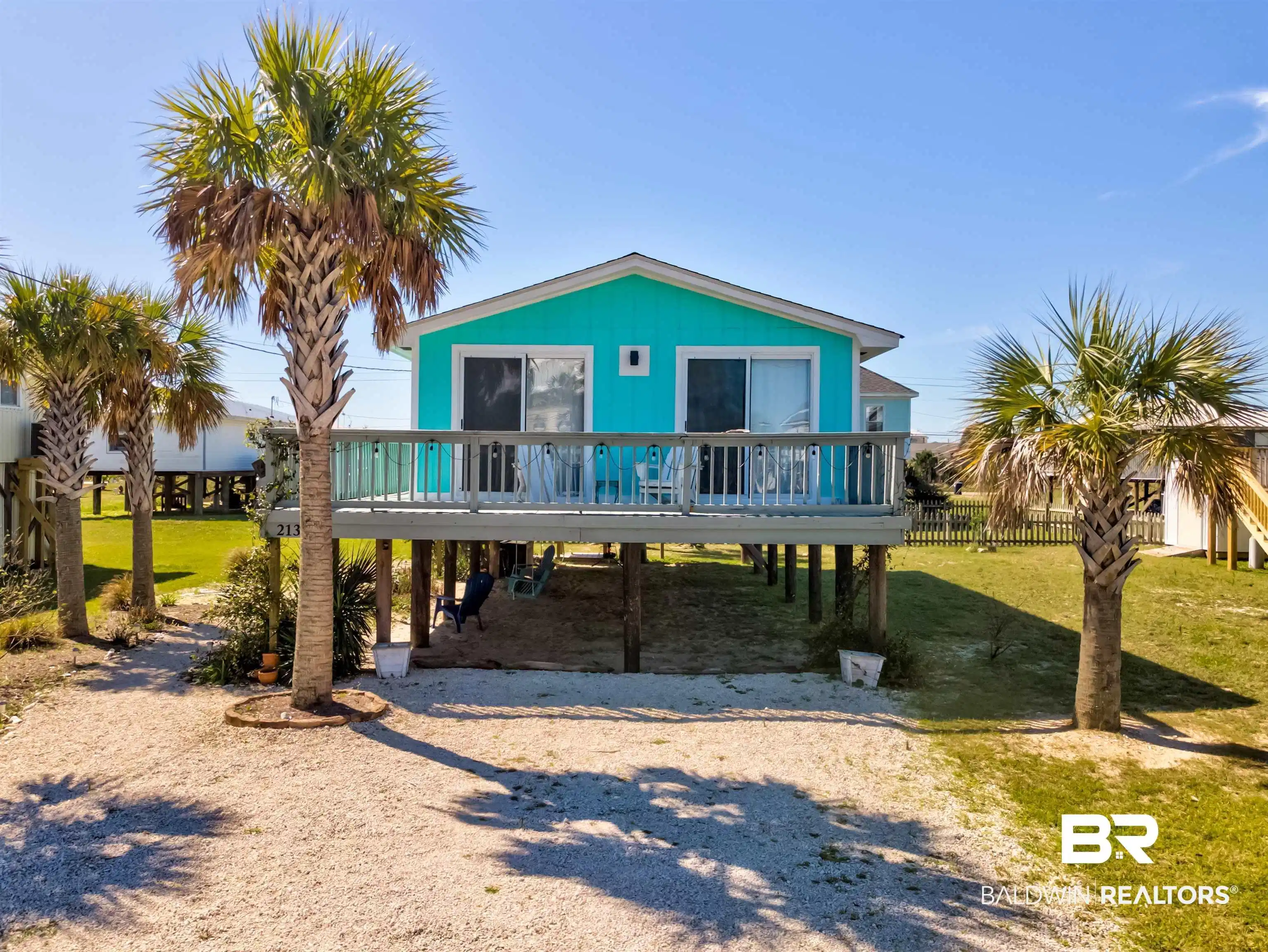 Image 1: Coastal inspired home with a deck, a carport, a front yard, and driveway