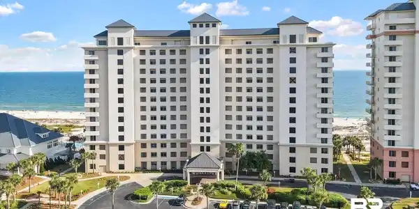 Image 2: View of apartment building / complex with view of water and beach and uncovered parking