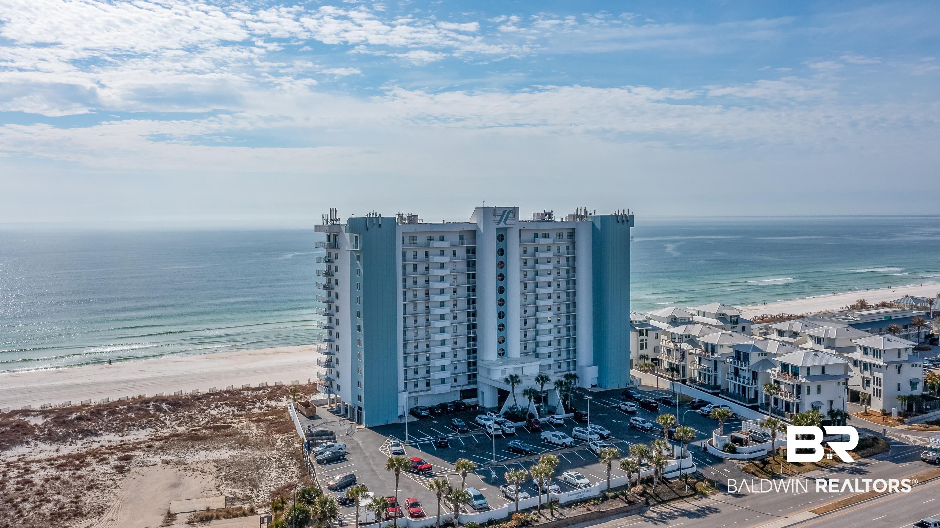 Image 1: Multistory building with light blue and white exterior, featuring a beachfront location directly on a sandy shore