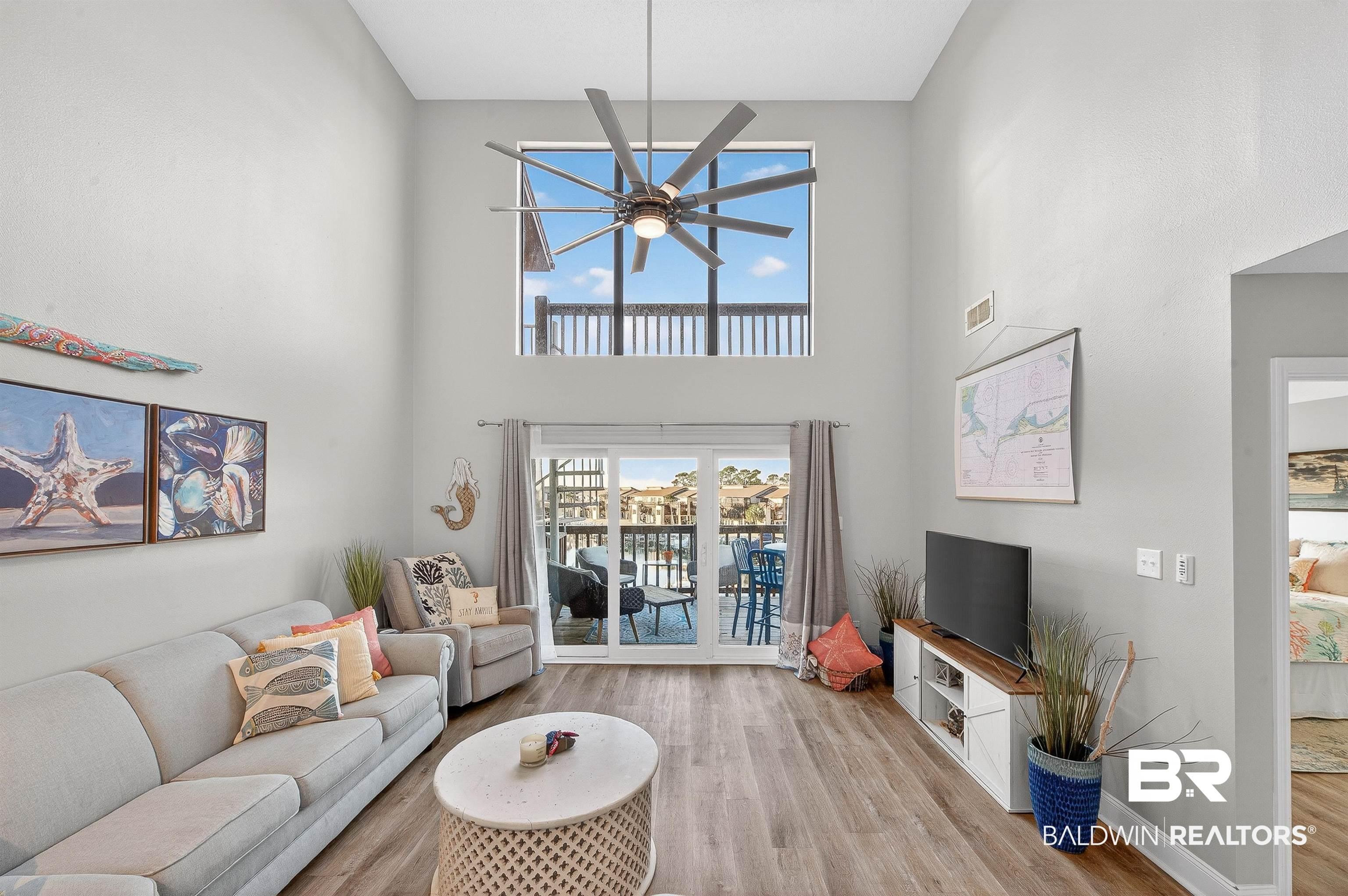 Image 3: Living area with wood finished floors, ceiling fan, and a towering ceiling
