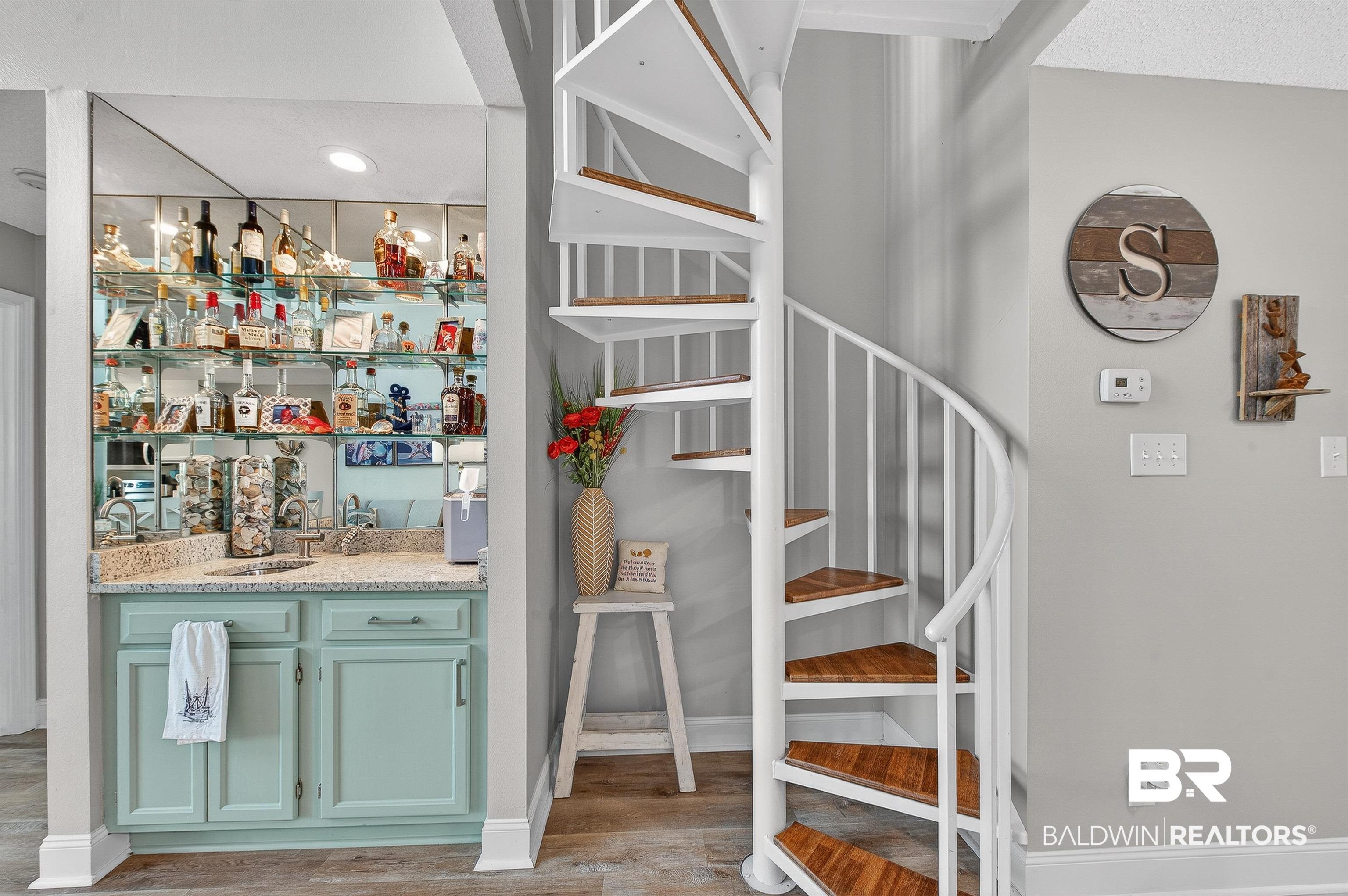 Image 4: Indoor wet bar featuring light wood-style floors, stairway, and light stone countertops
