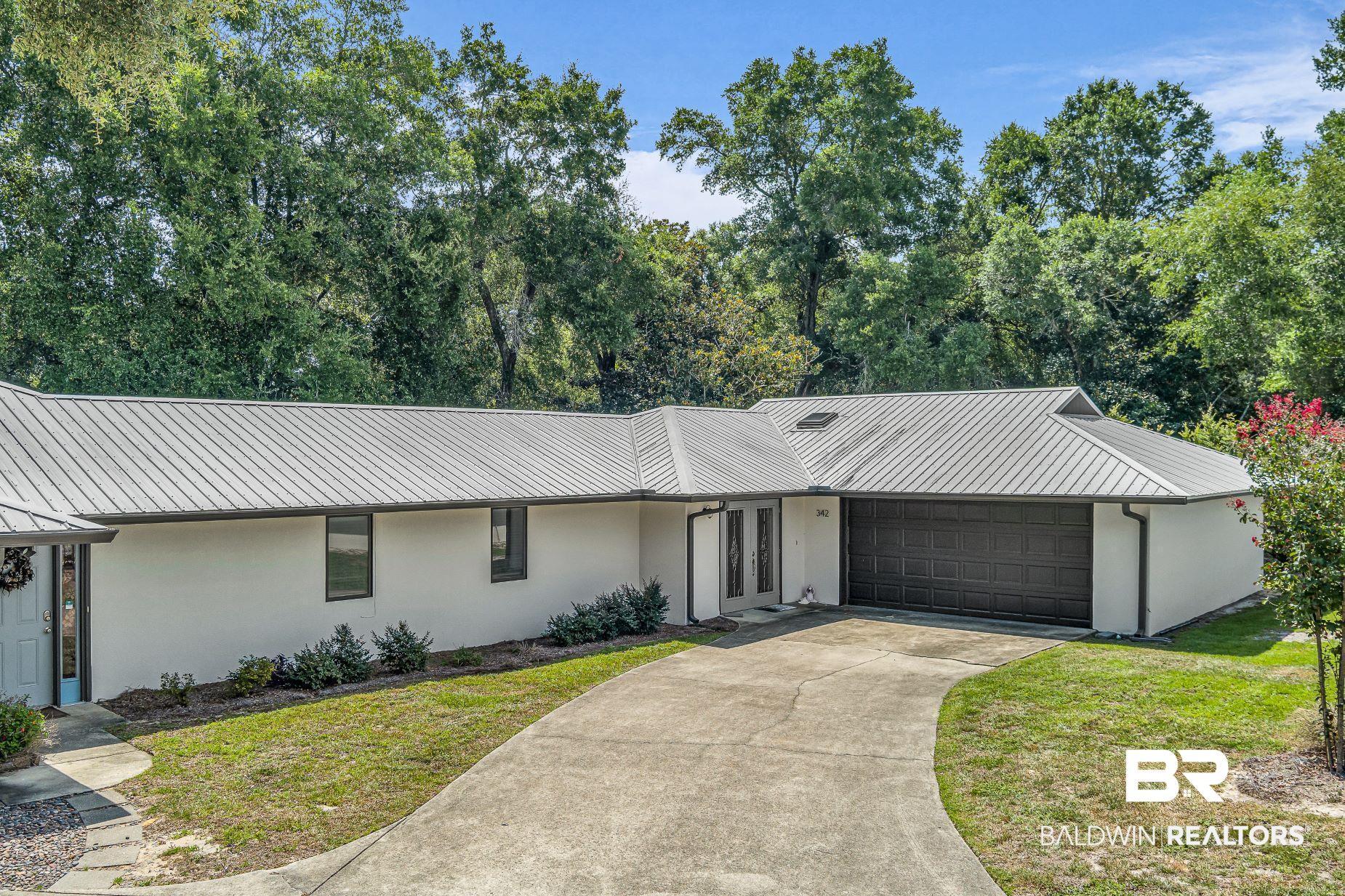 Image 1: View of front facade featuring stucco siding, a metal roof, and an attached garage