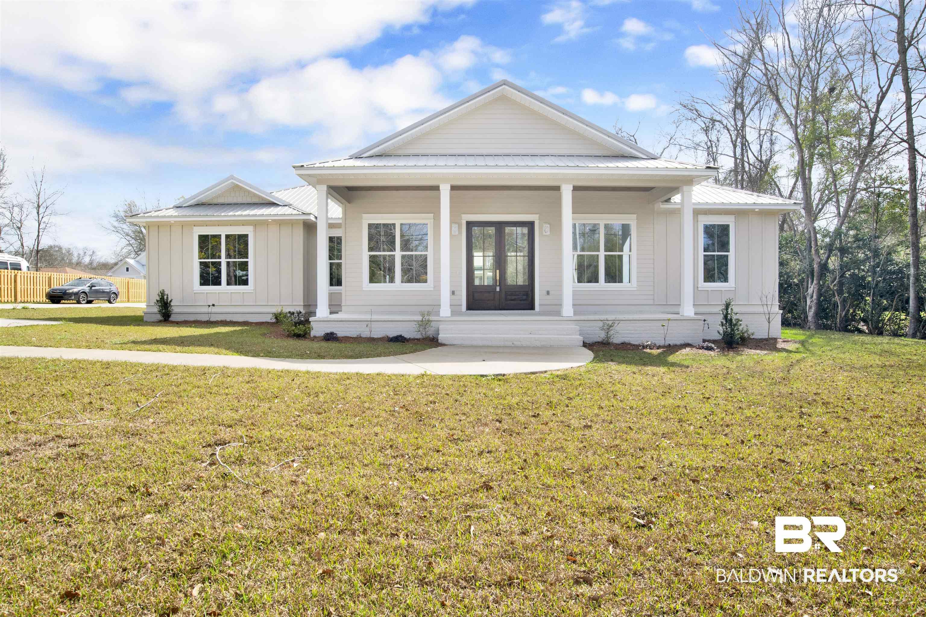Image 1: View of front of home with board and batten siding, covered porch, a front yard, and french doors
