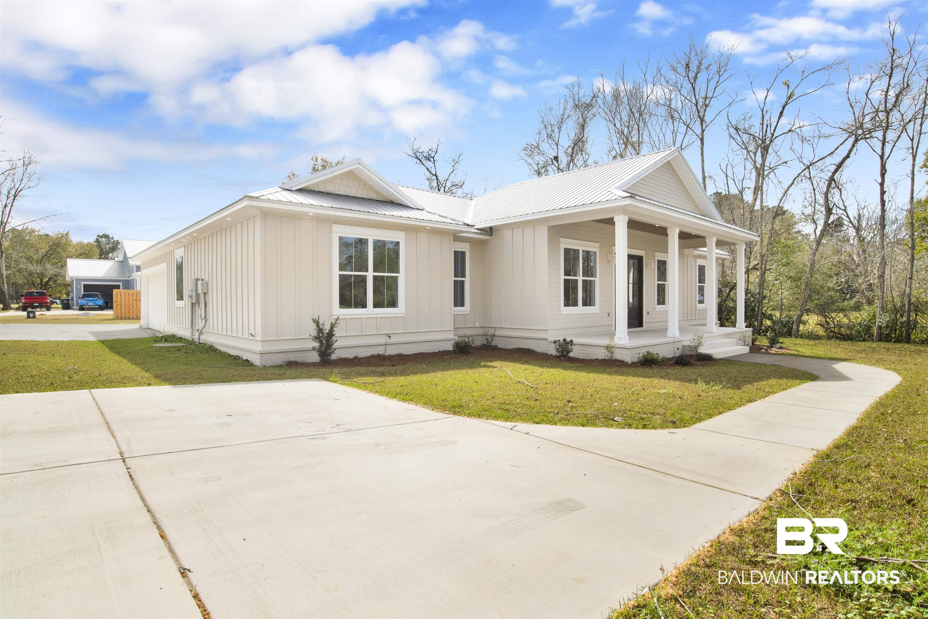 Image 3: View of front of property with a front yard, covered porch, and board and batten siding