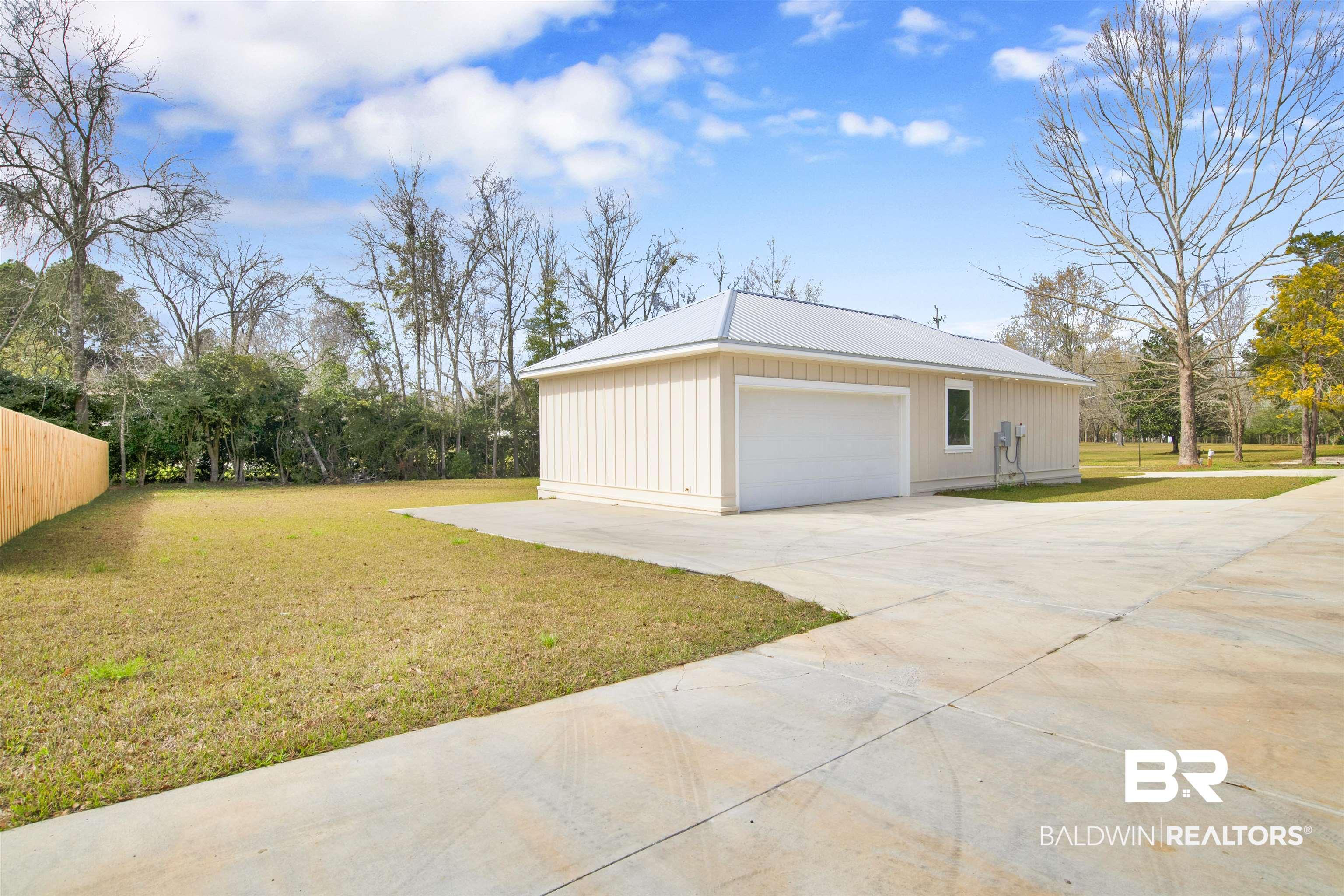 Image 4: View of side of home with a yard, a metal roof, and driveway