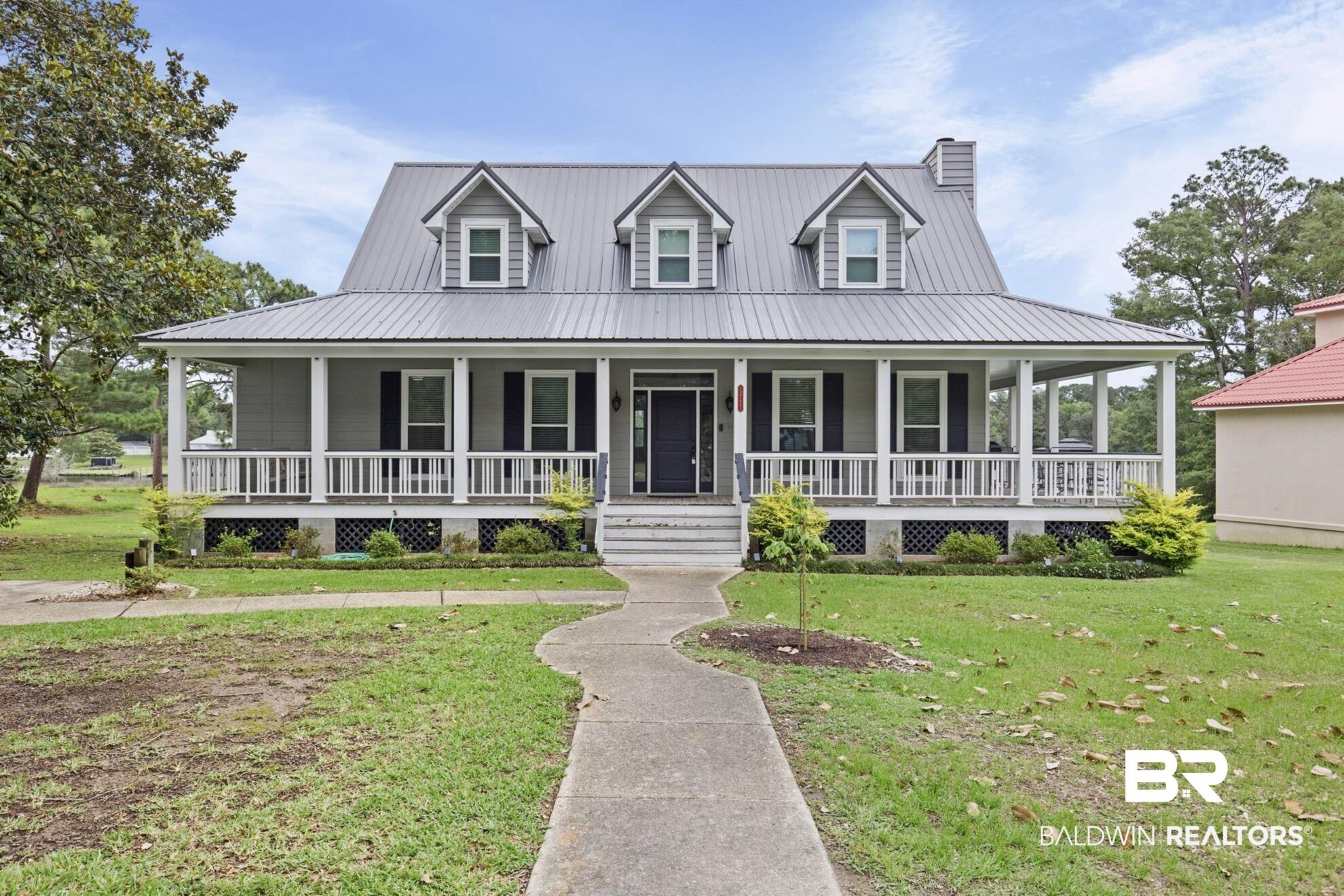 Image 1: Exterior featuring a wide covered porch with white railing, gray siding, a metal roof, and three dormer windows