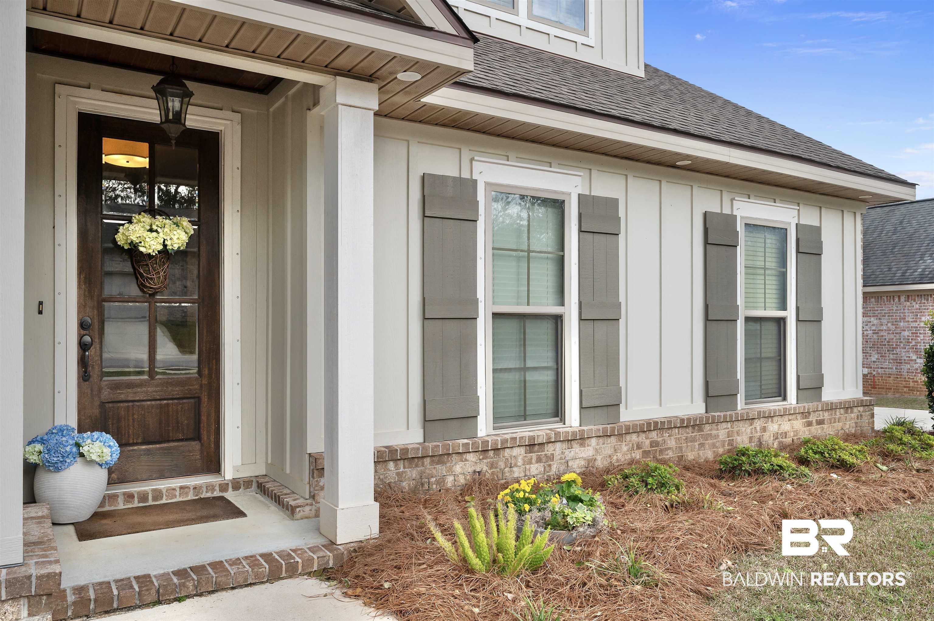 Image 3: Doorway to property featuring a shingled roof, board and batten siding, and brick siding