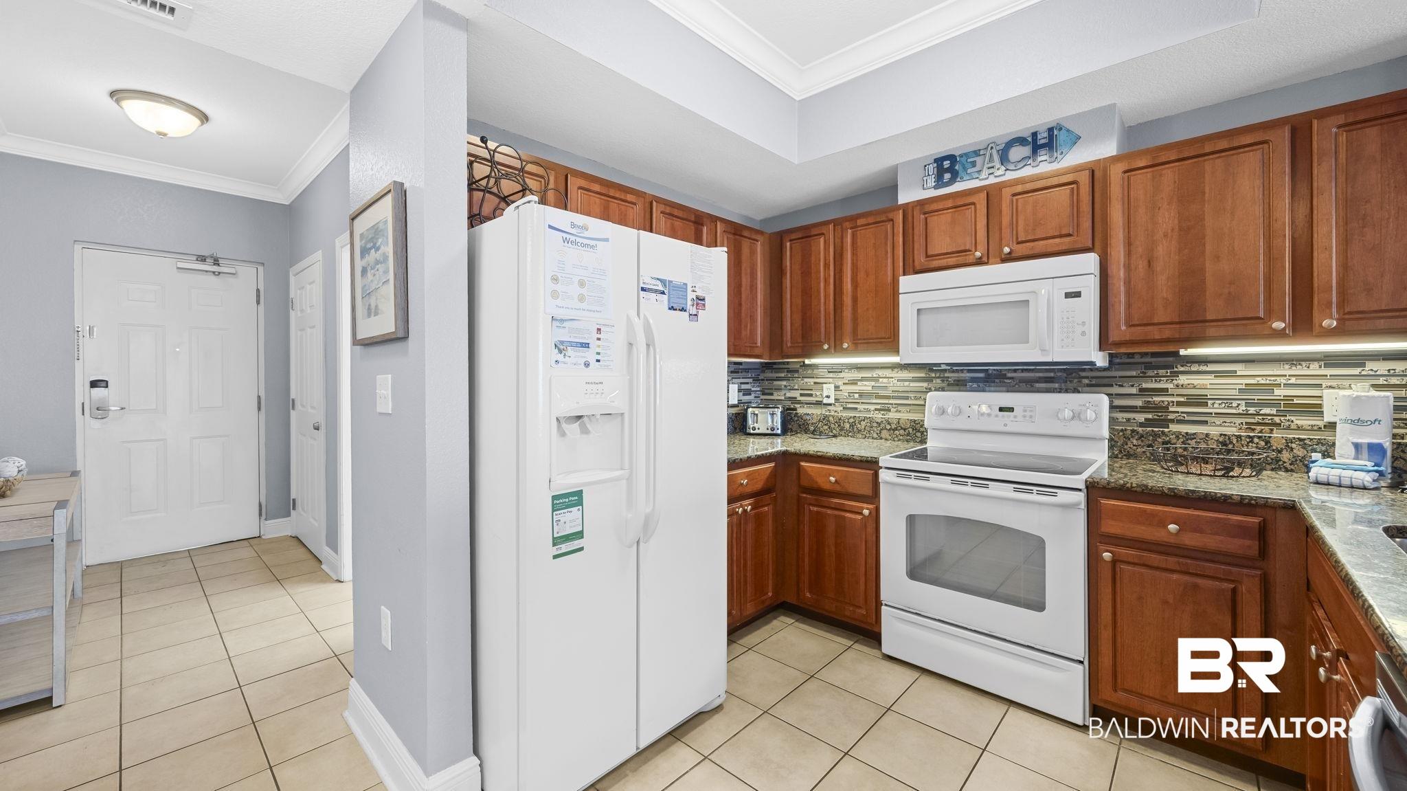 Image 4: Kitchen featuring wood cabinetry, granite-style countertops, and a full suite of white appliances