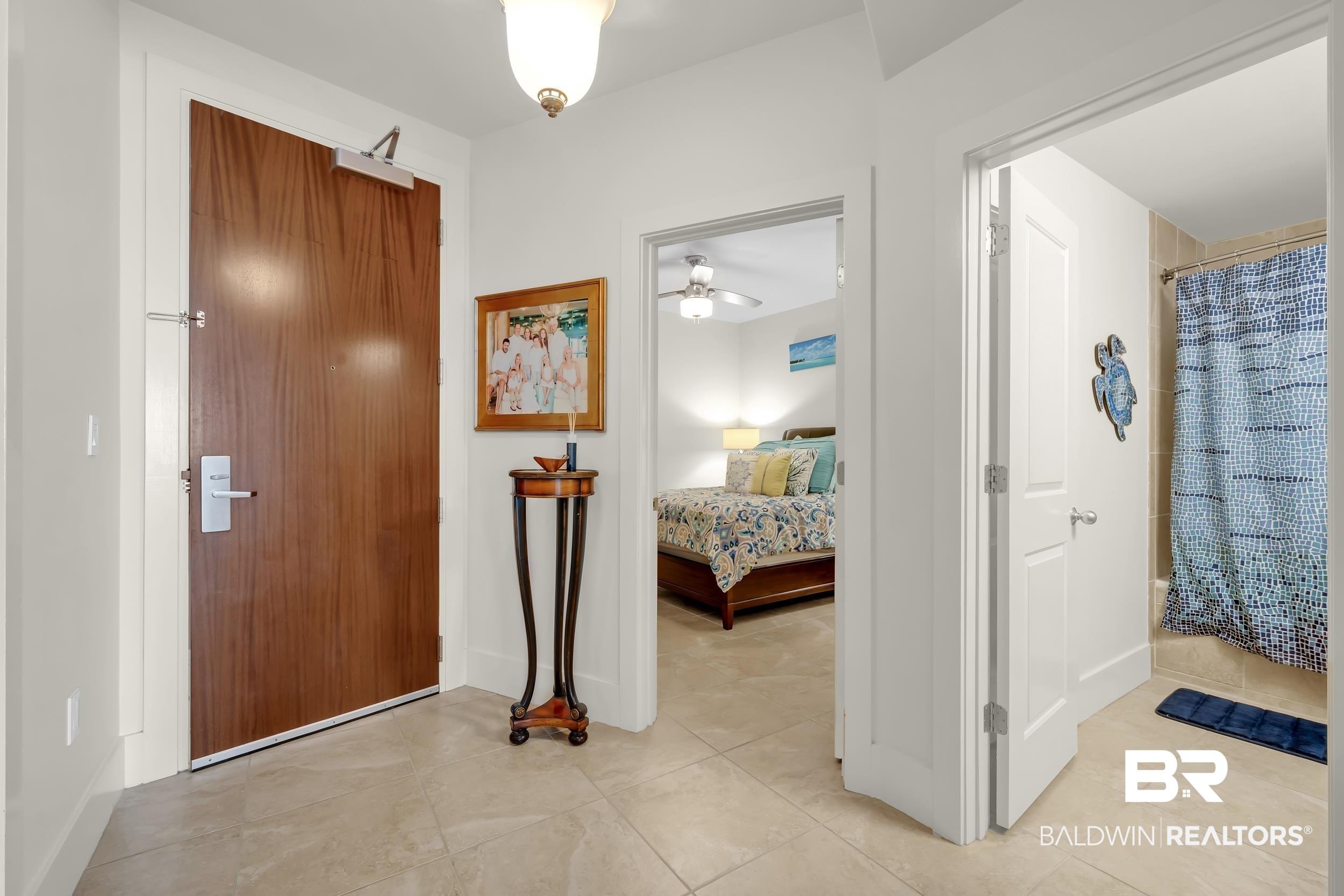 Image 3: Entry foyer featuring a wood-finish door with a door closer, tile flooring, and white baseboards