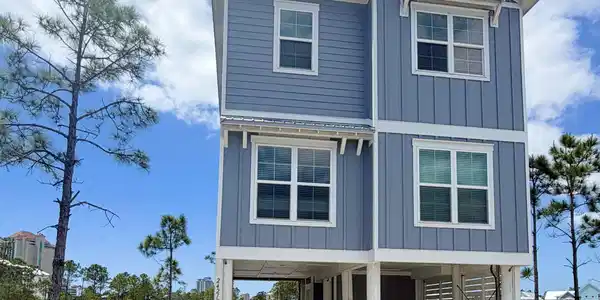 Image 2: Two-story coastal-style residence featuring blue siding and white trim