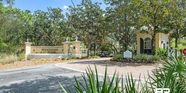 Image 2: Entryway featuring "Martinique" signage, a yellow-painted guardhouse with dark green shutters, and an asphalt drive with a paver stone turn-around