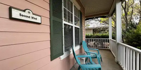 Image 3: Covered front porch featuring a plank ceiling, concrete flooring, decorative railing, horizontal siding, and functional louvered shutters