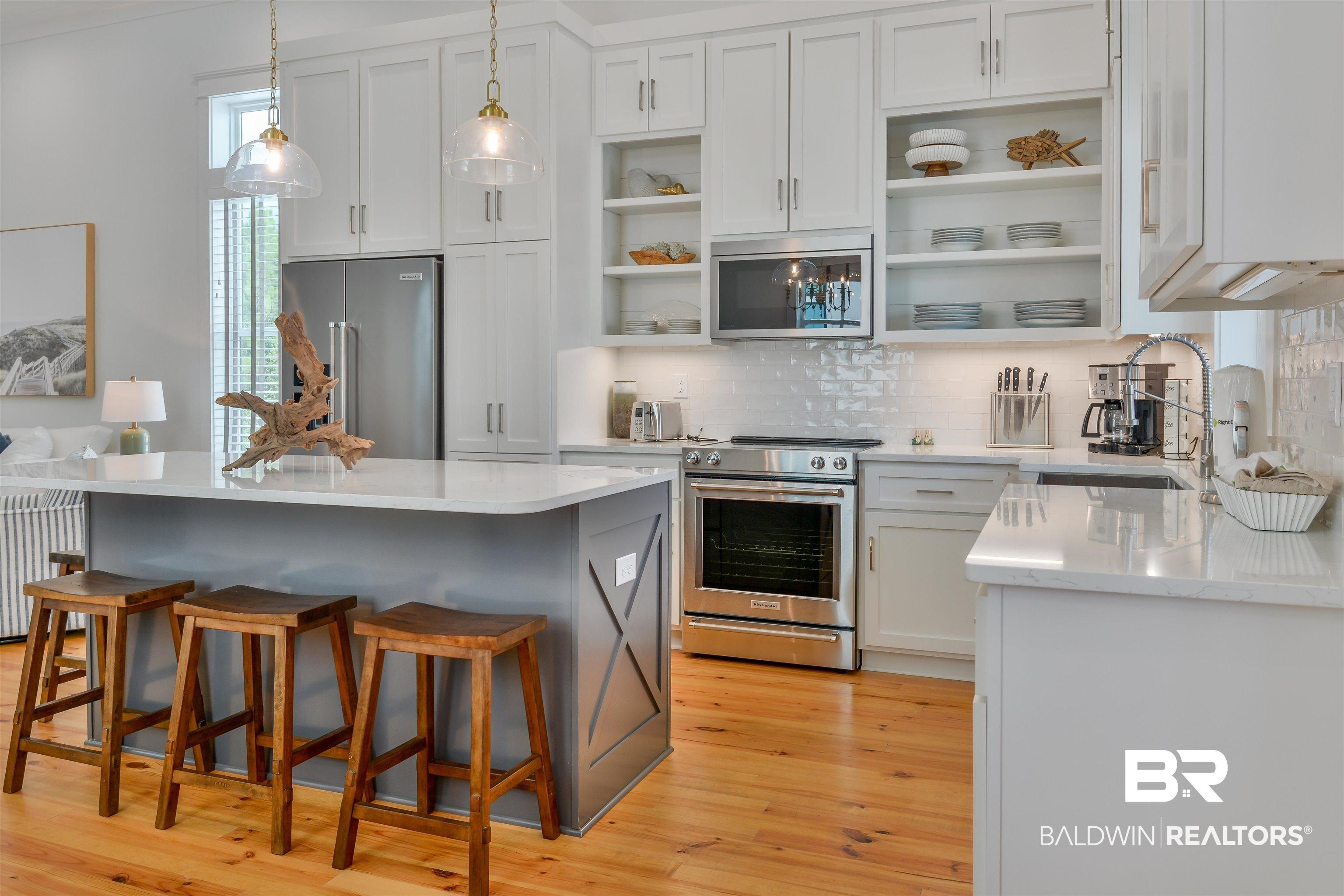 Image 3: Kitchen featuring stainless steel appliances, decorative light fixtures, a kitchen island, and light wood-type flooring