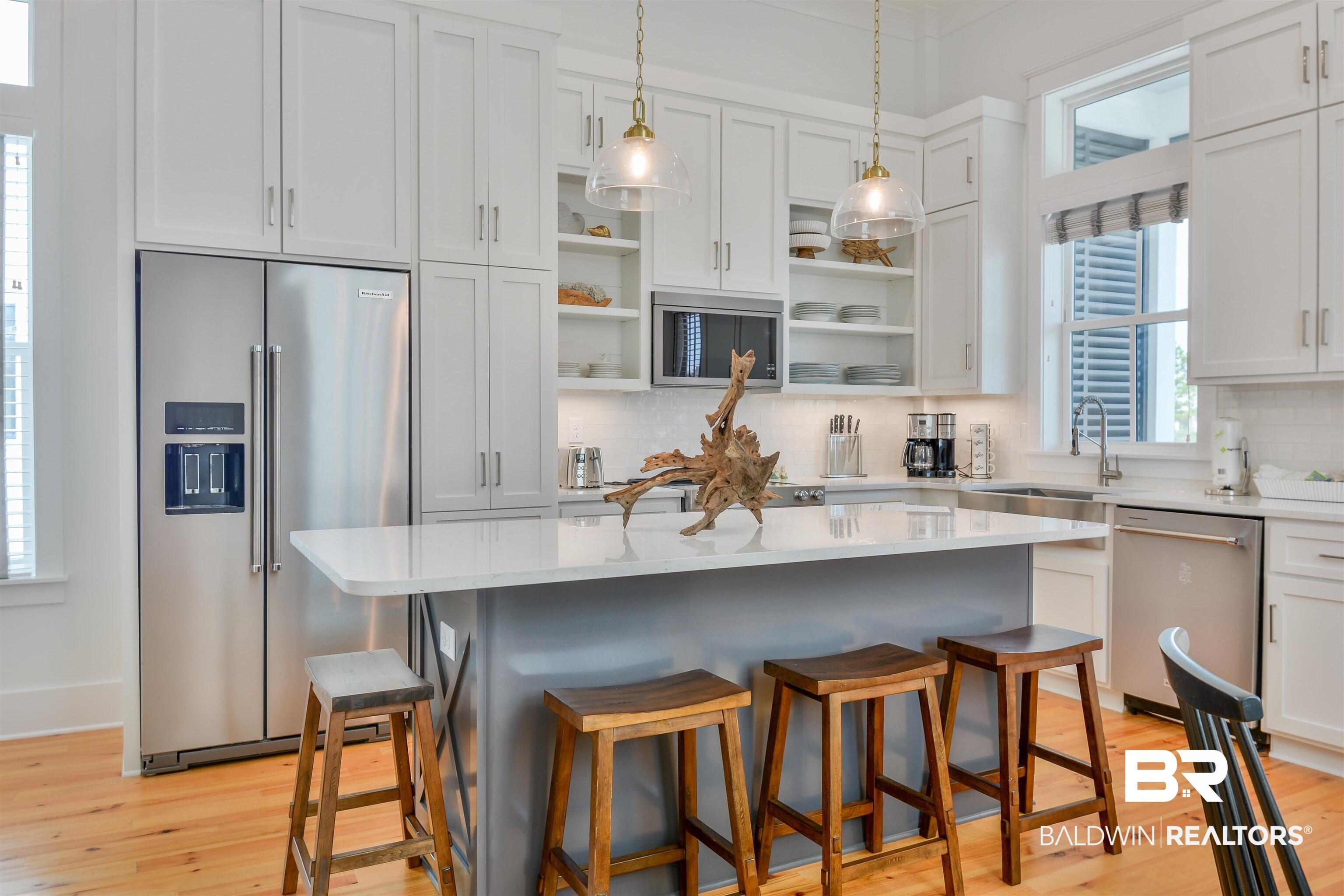 Image 4: Kitchen with light wood-type flooring, a kitchen island, backsplash, and stainless steel appliances