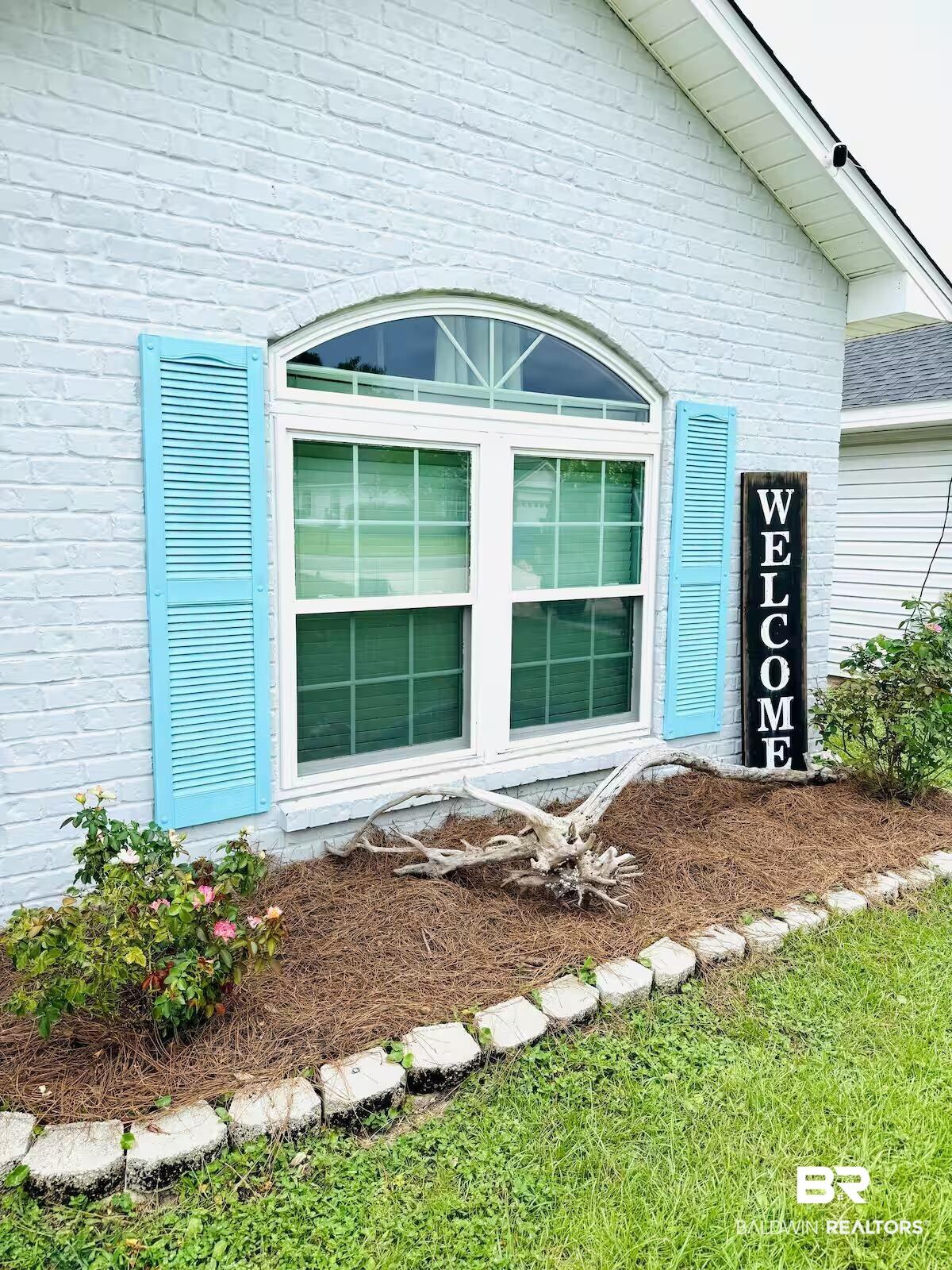 Image 2: Light-colored brick exterior with an arched window featuring louvered shutters