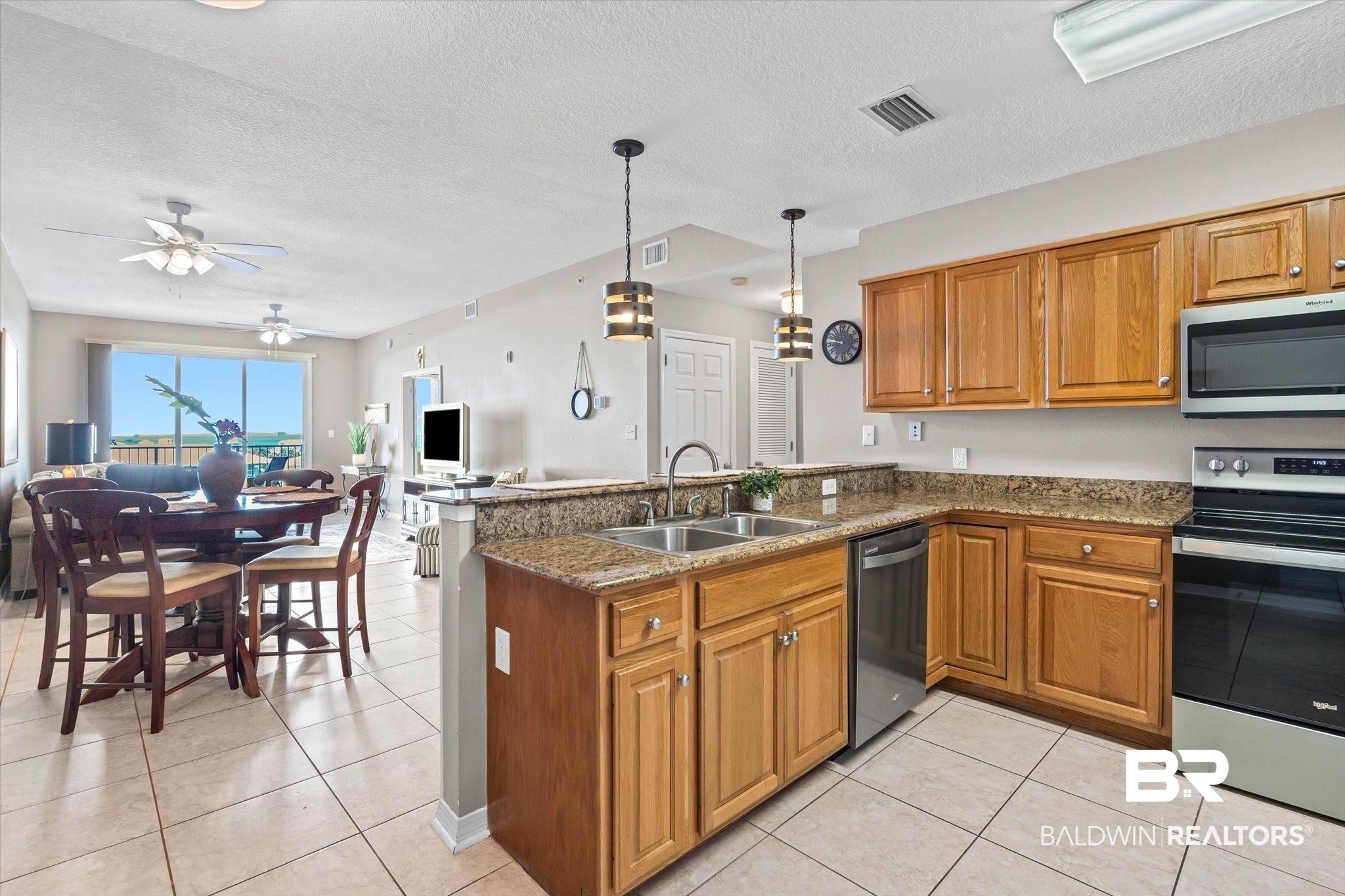 Image 4: Kitchen featuring wood cabinetry, appliances with stainless steel finishes, a peninsula with eat-up breakfast bar