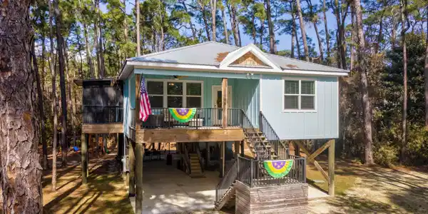 Image 2: Coastal inspired home featuring a carport, a sunroom, dirt driveway, a metal roof, and a deck