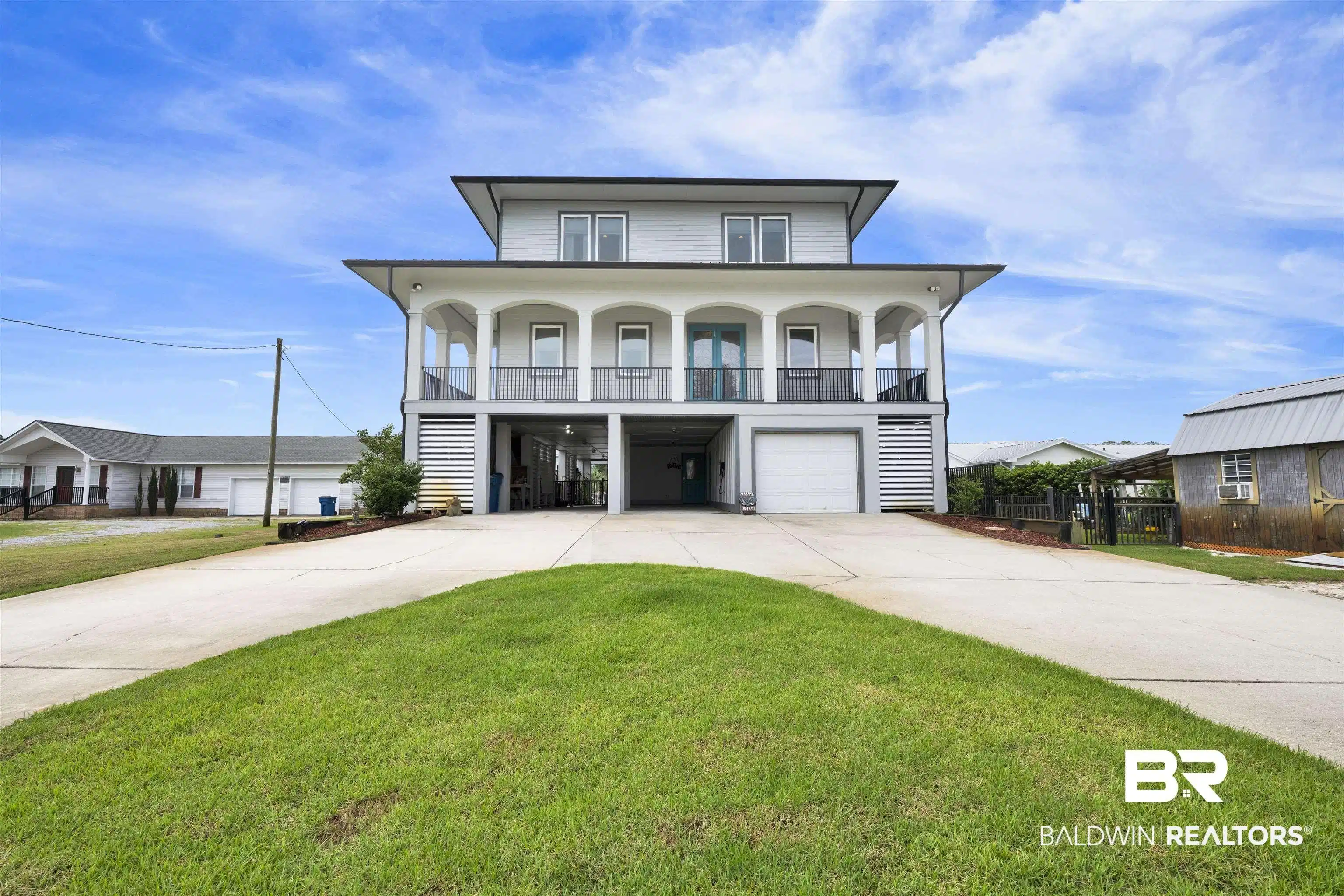 Image 1: Elevated coastal-style residence featuring a prominent covered balcony with arched openings and dark railings