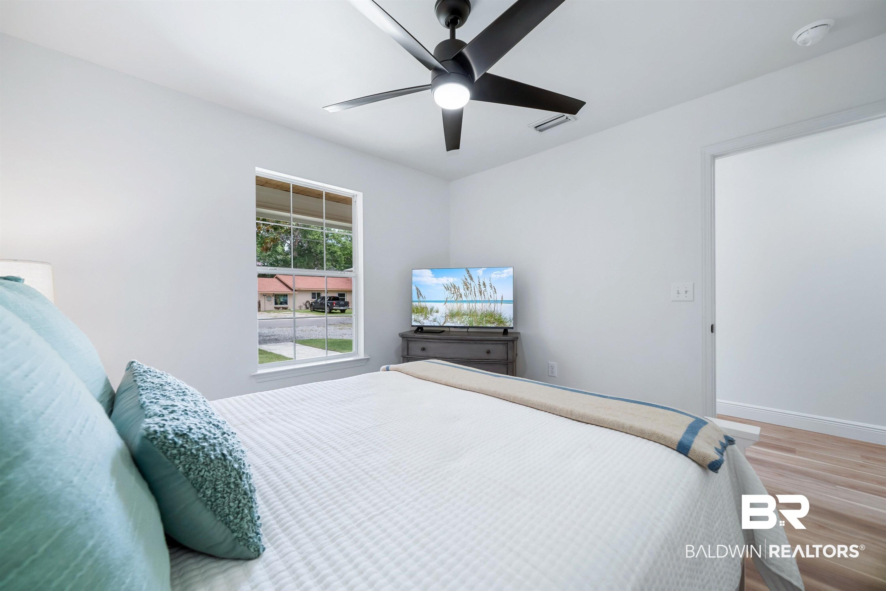 Image 3: Bright interior space featuring a multi-pane window, flush-mount ceiling fan, and wood-finish flooring