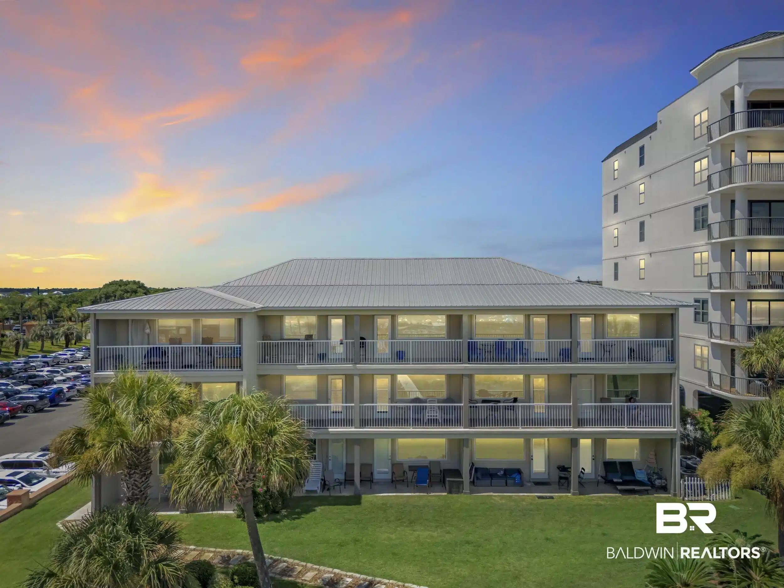 Image 1: Multi-story condominium building featuring private balconies, a metal roof, and a manicured lawn