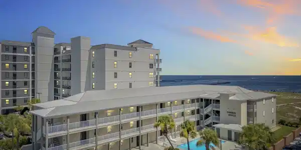 Image 3: Coastal condominium buildings featuring multiple stories, private balconies, and a swimming pool surrounded by palm trees