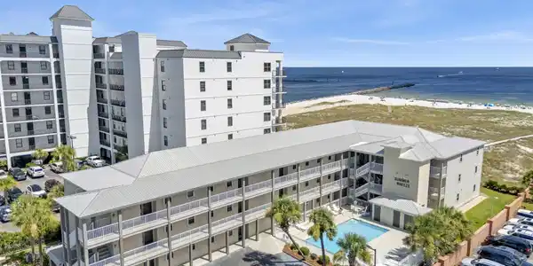 Image 4: Coastal multi-story residential building with private balconies and a swimming pool, positioned near a sandy beach and the ocean