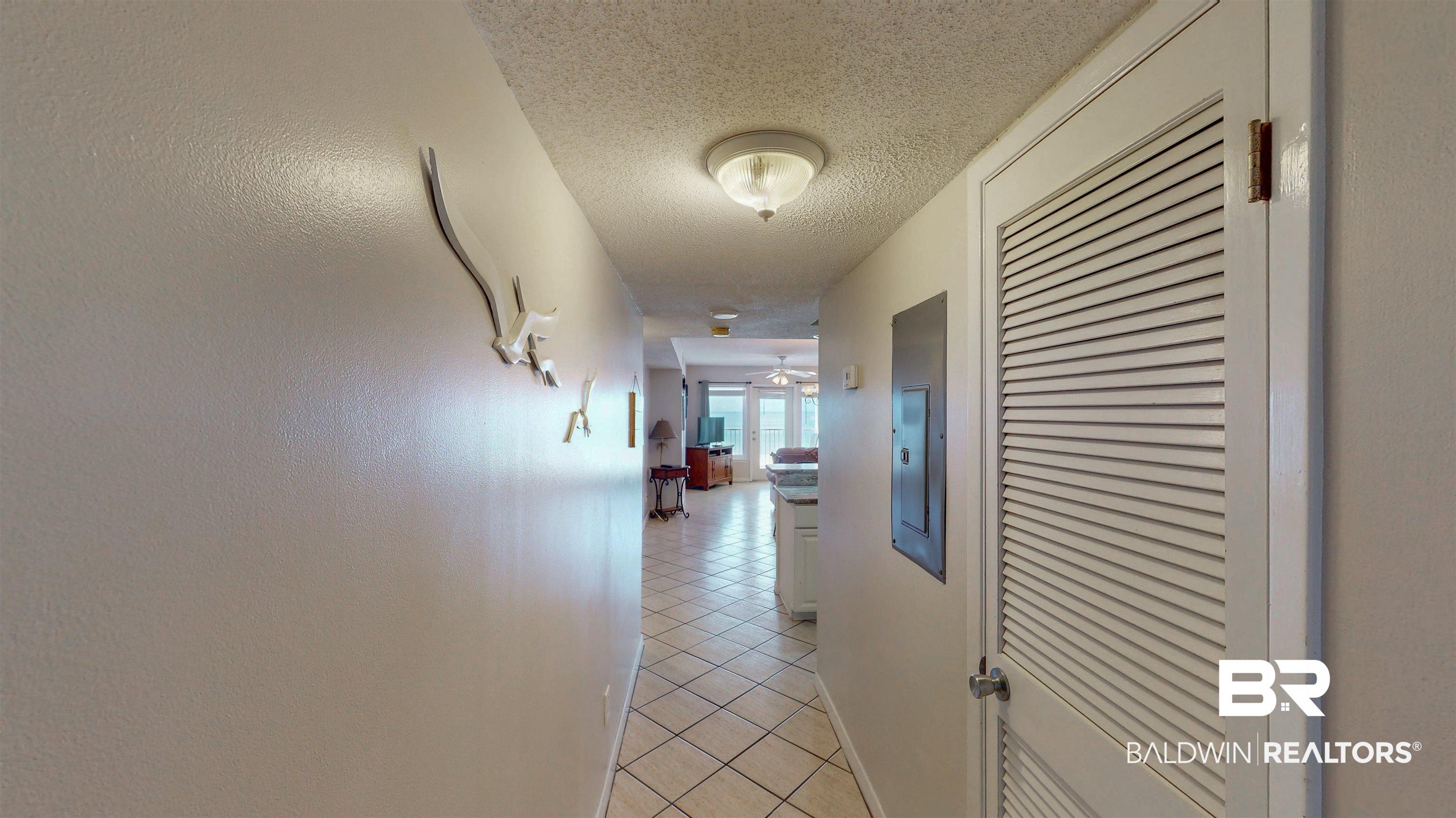 Image 3: Hallway featuring a textured ceiling, light tile patterned floors, and electric panel