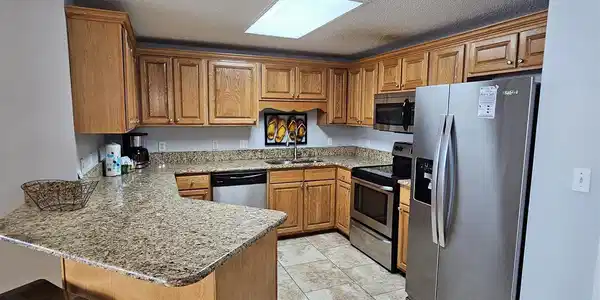 Image 3: Kitchen with stainless steel appliances, a peninsula, a breakfast bar, light stone countertops, and a textured ceiling