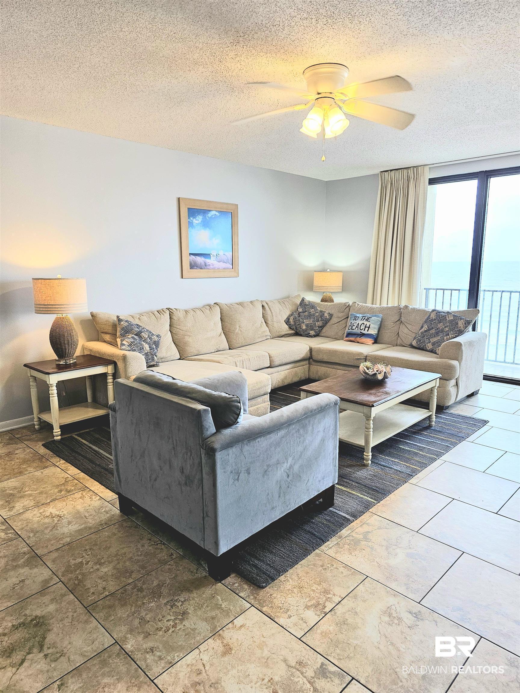 Image 4: Living area featuring a textured ceiling, ceiling fan, and tile patterned floors