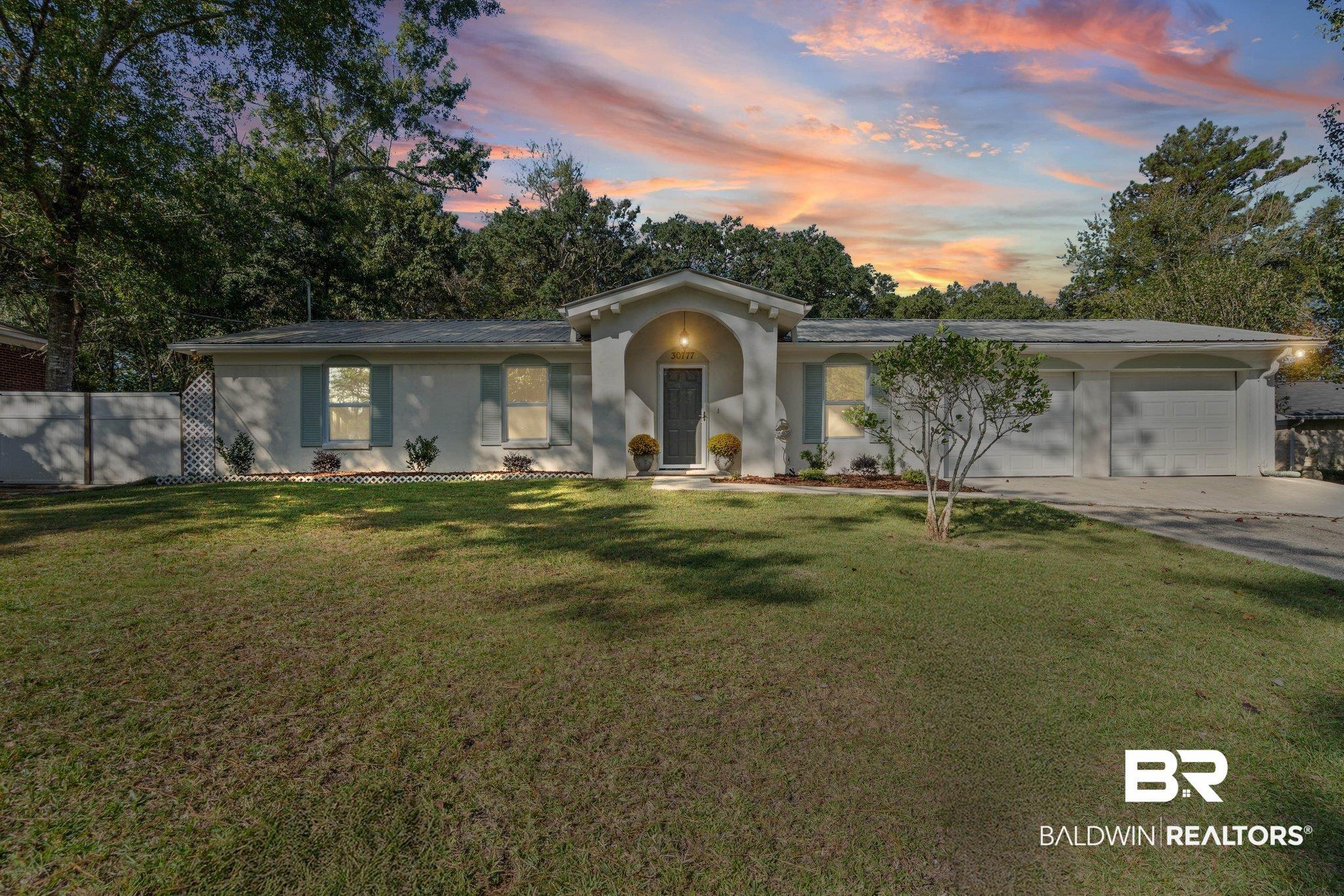 Image 1: Ranch-style house with a lawn, an attached garage, stucco siding, and driveway