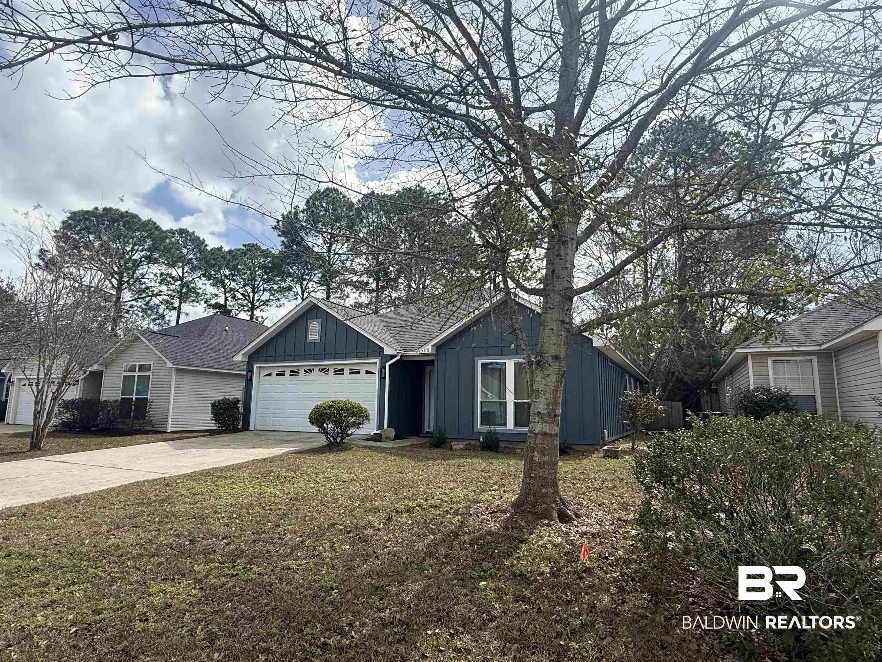 Image 2: Ranch-style home featuring board and batten siding, concrete driveway, an attached garage, and a front yard