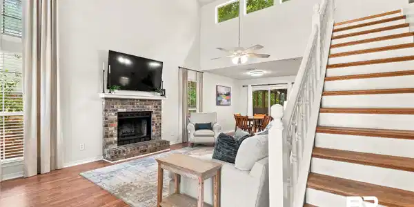 Image 2: Vaulted ceilings in this living area featuring wood-finish flooring and a brick fireplace
