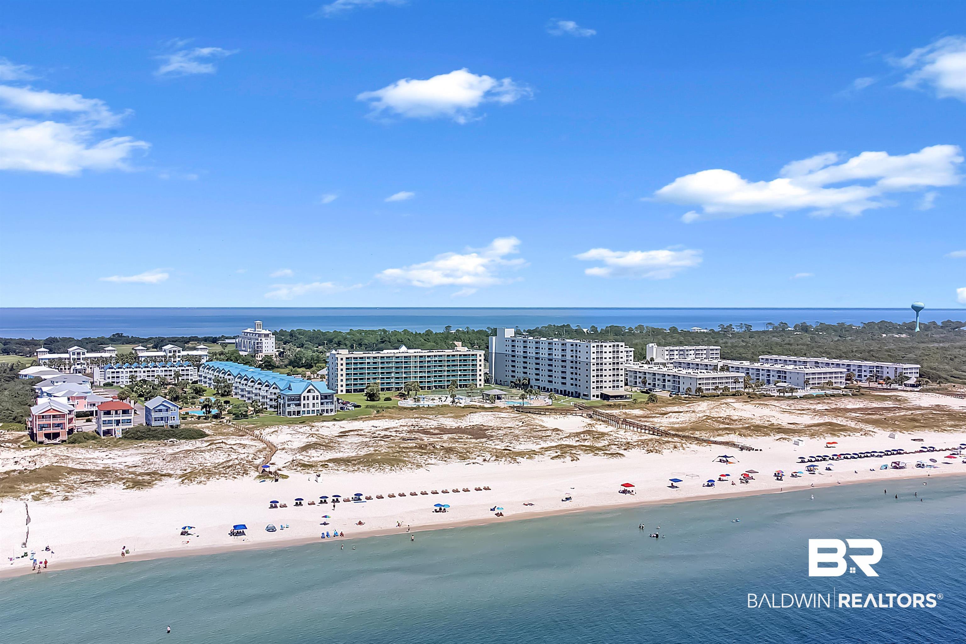 Image 2: Expansive coastal landscape featuring a broad sandy beach, clear blue water, and multiple beachfront condominium buildings