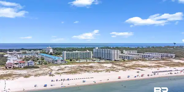 Image 2: Expansive coastal landscape featuring a broad sandy beach, clear blue water, and multiple beachfront condominium buildings