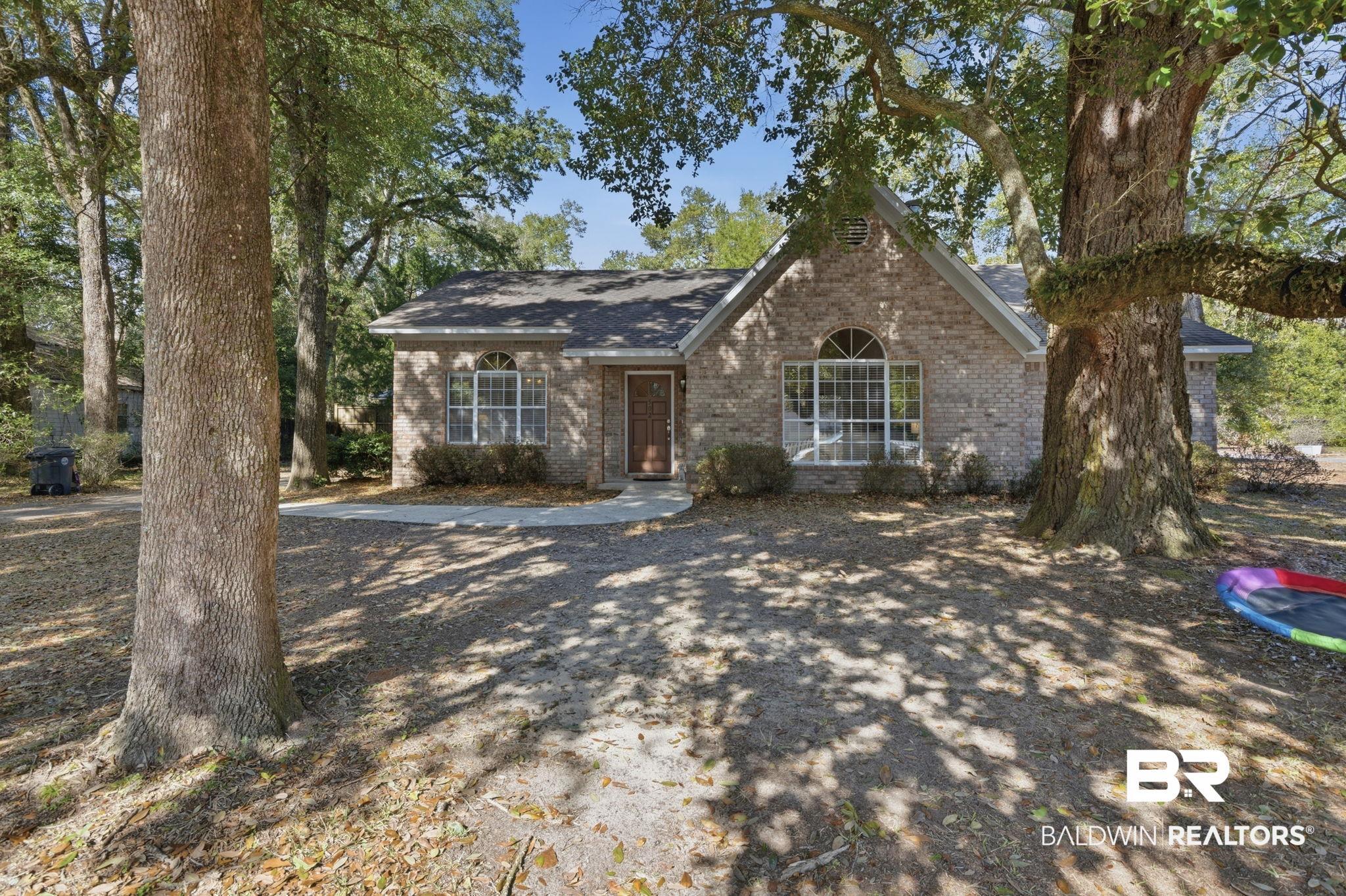 Image 3: View of front facade featuring brick siding and roof with shingles