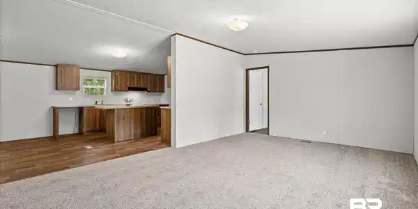 Image 2: Open concept living area with carpeting, wood-finish flooring, and natural wood cabinetry