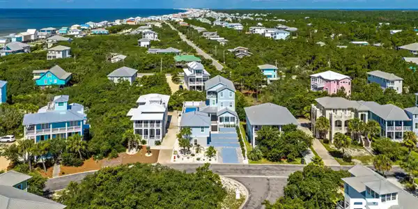 Image 4: Coastal neighborhood featuring residences surrounded by dense foliage and paved roadways