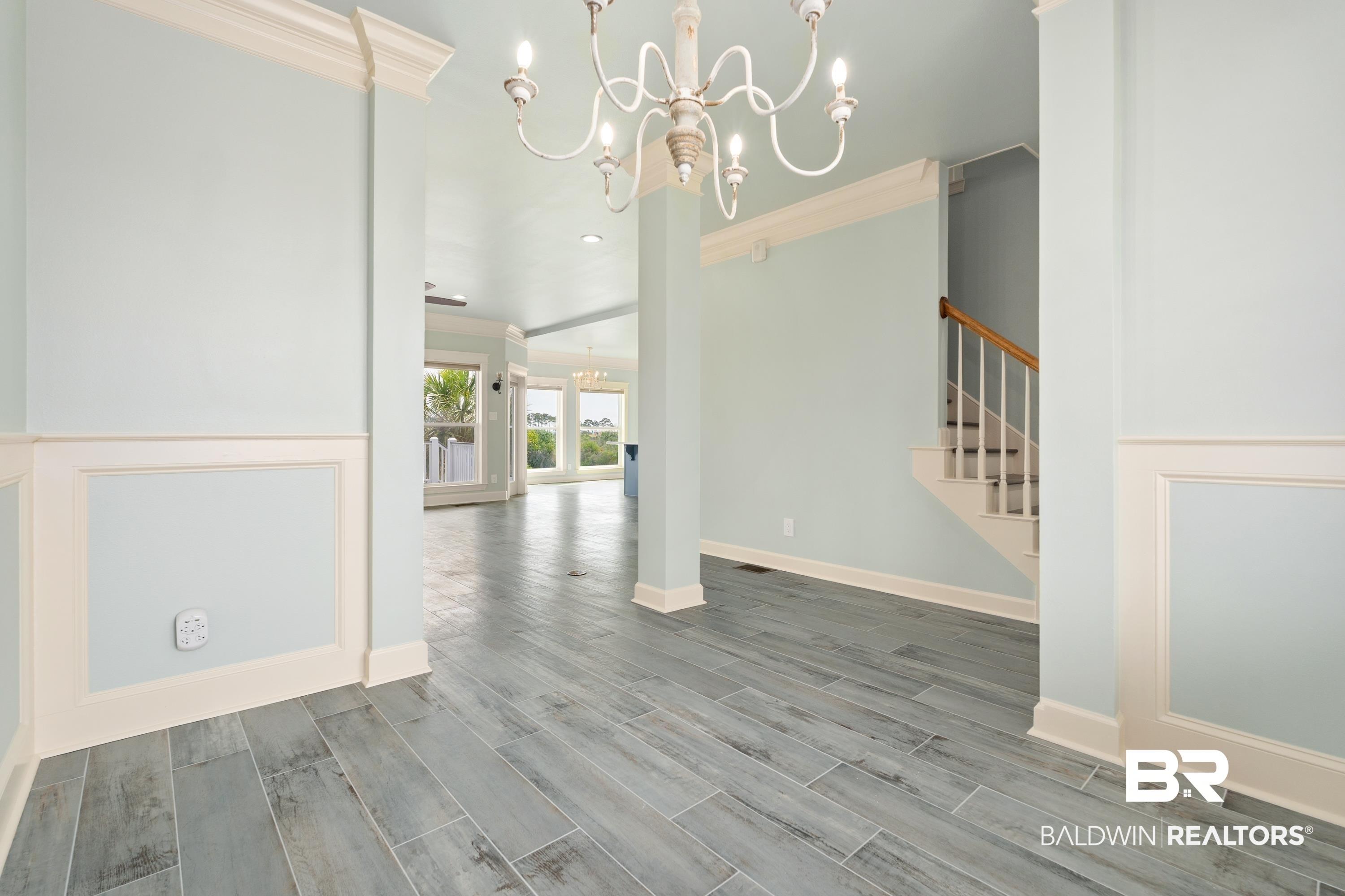 Image 4: Entryway featuring wood-finish flooring, wainscoting, crown molding, and a chandelier