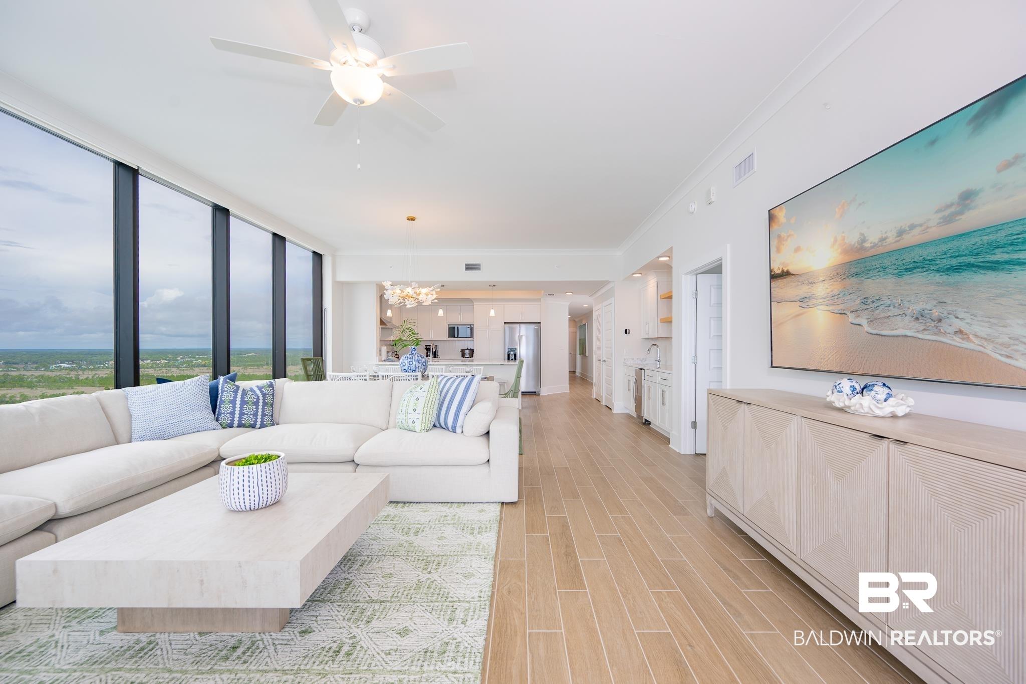 Image 3: Expansive living area featuring floor-to-ceiling windows and wood-finish flooring