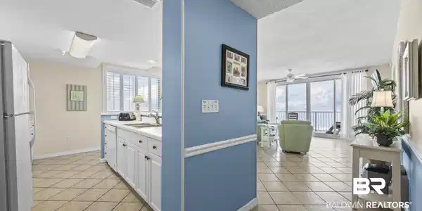 Image 2: Open-concept living space with tile flooring throughout, featuring a kitchen with white cabinetry and a living area with sliding glass doors opening to a balcony