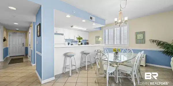 Image 3: Open-concept kitchen and dining area featuring white cabinetry, a breakfast bar with beadboard paneling, and tile flooring